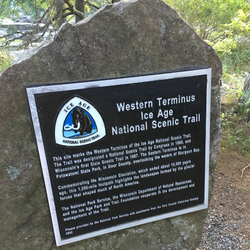 A rock with a sign about the Ice Age Trail attached to it.