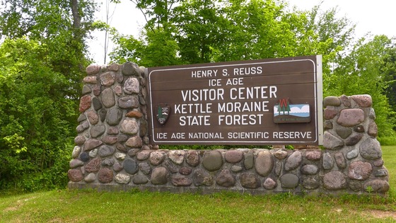 The entry sign at the The Kettle Moraine State Forest ? Northern Unit surrounded by green grass and trees.