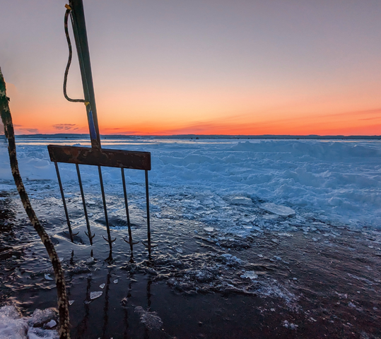 spear on icy lake at sunrise