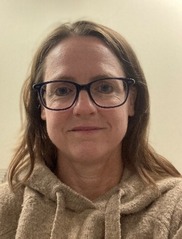 A headshot of a woman with glasses wearing a grey sweatshirt. 