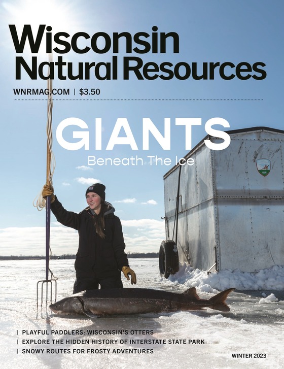 cover of WNR magazine winter issue, woman holding a spear with a sturgeon on the ice