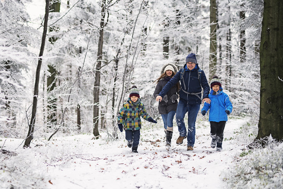 A family hikes through a snowy winter landscape. 