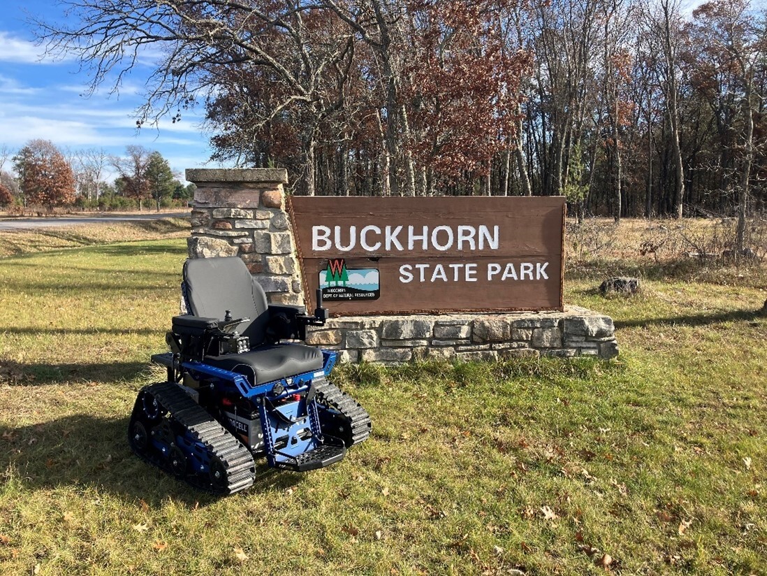 An outdoor wheelchair positioned next to the welcome sign at Buckhorn State Park. 