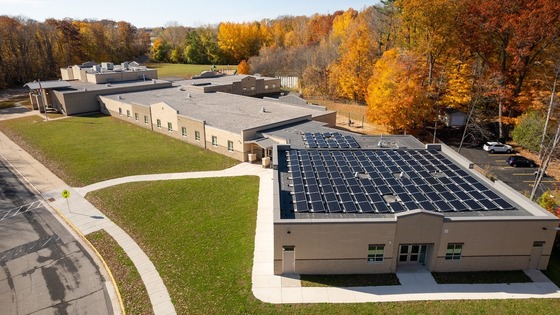 An aerial photo of a school building roof with a large solar panel array. 