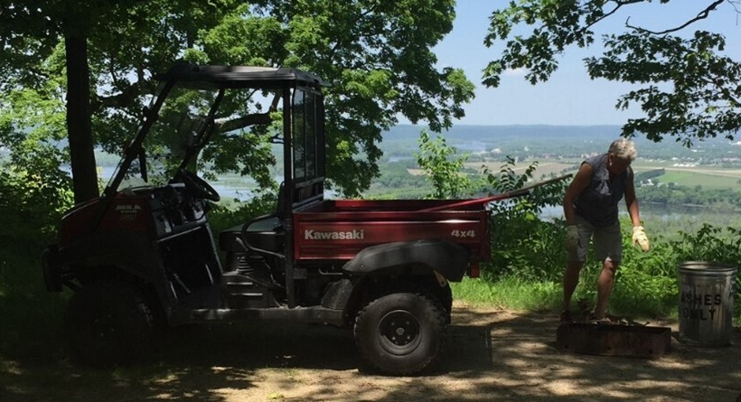 a male campground host cleaning up a state park campsite with a red UTV behind him