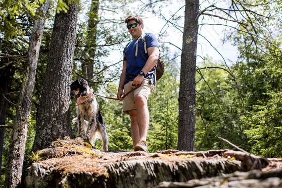 A man stands on a rock with his dog on the leash at a state park. 