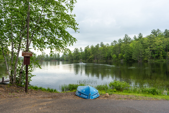 A fishing boat traveling across the calm waters of Escanaba Lake as viewed from the boat launch parking lot. 