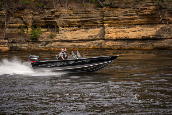 two conservation wardens riding on a boat with rock structures in the back