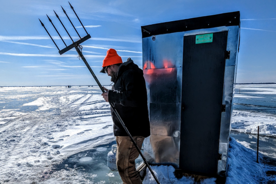 A sturgeon spearer hold a spear while on the ice. 