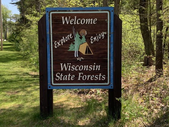 A wooden entrance sign welcomes visitors to explore and enjoy Wisconsin?s state forests,