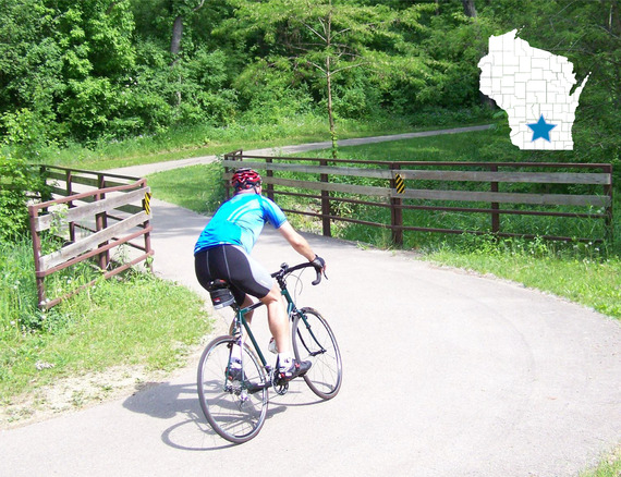 A man biking on a trail with Wisconsin map