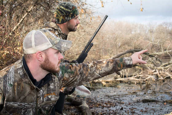 two male waterfowl hunters wearing camouflage in wetlands