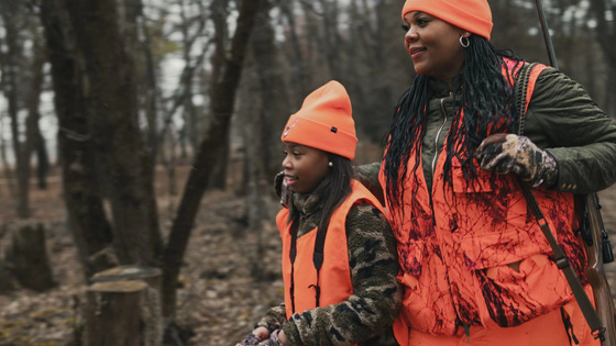 Young girl wearing blaze orange with her mom wearing blaze orange while hunting in a forest