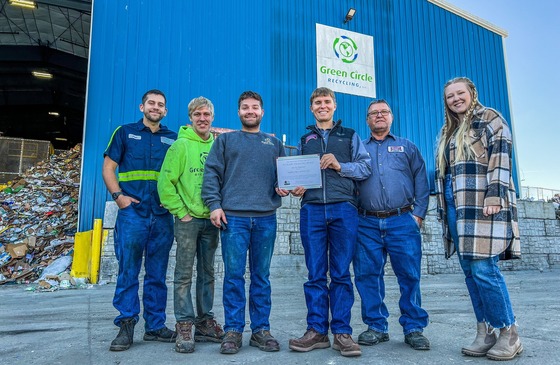 Green Circle Recyling team standing outside of their recycling center holding their award