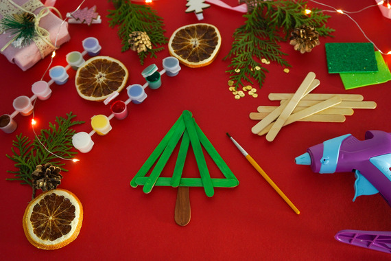 Various ornaments and holiday decorations sitting atop a table covered with a red table cloth. 