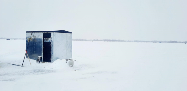 An ice shanty sits on a frozen lake. 