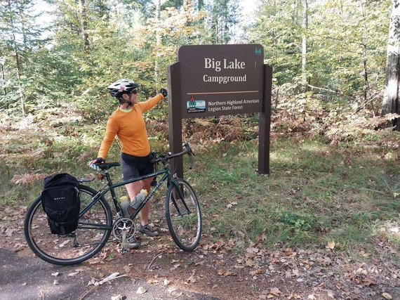 Woman standing with bike by a campground sign