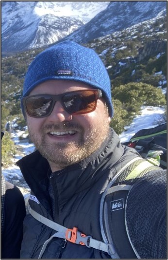 An individual in a winter hat and hiking gear. 