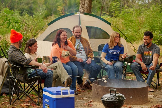 Six people sitting around a campfire during fall