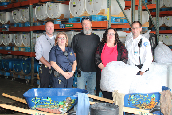 Five people pose for a group photo while standing in a warehouse.
