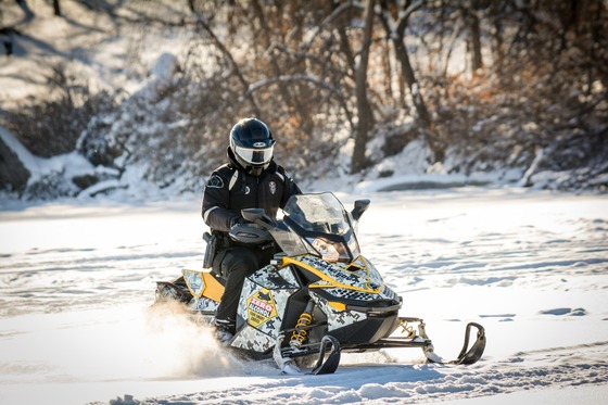 Wisconsin conservation warden riding a snowmobile and wearing a helmet
