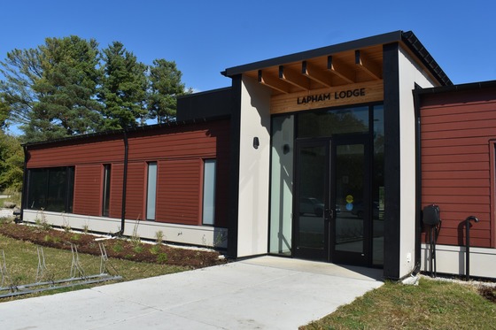 A red-sided building with a large, glass front entrance with the words "Lapham Lodge" above the door. 