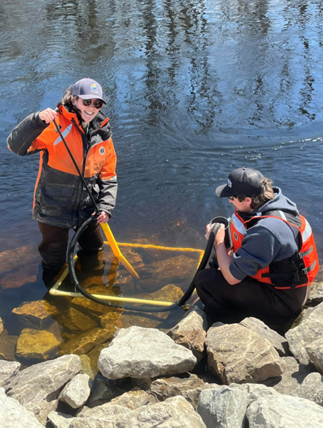 Sam Embersits works with a colleague to collect sturgeon eggs in the rocks of a waterbody