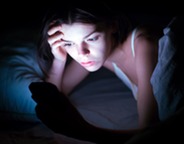 Girl in bed on cell phone at night
