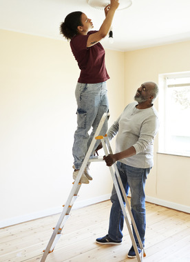Woman on ladder with man stabilizing