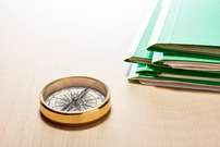 compass next to stack of folders on desk