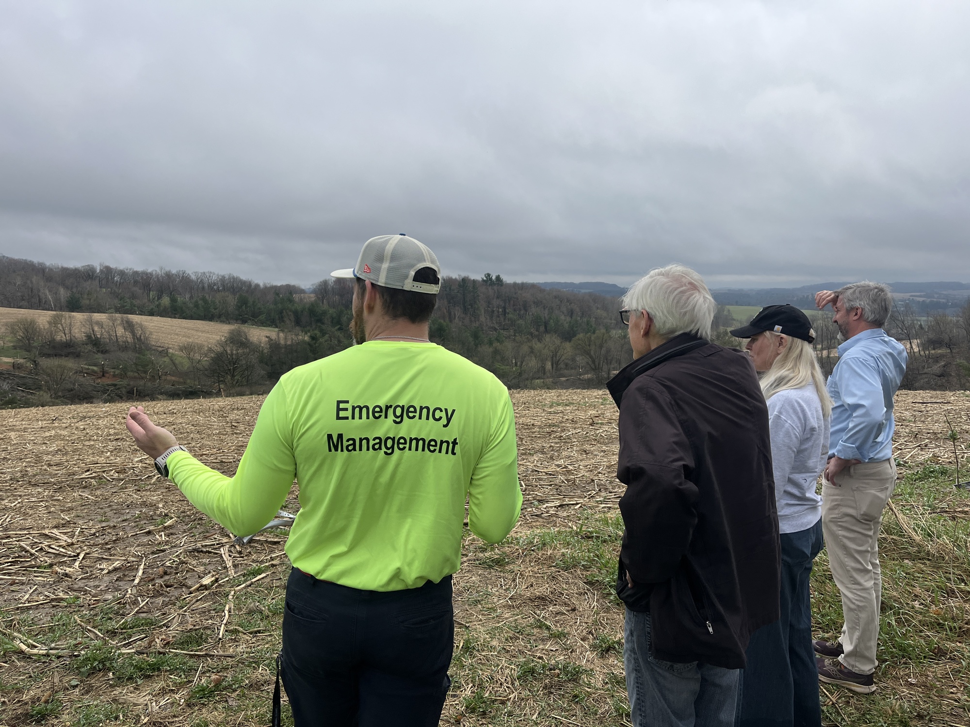 Gov. Evers looks out at field and storm damage with emergency management personnel