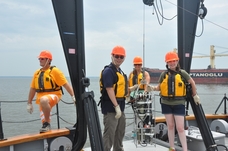 Teachers in hardhats and life jackets standing on deck of ship