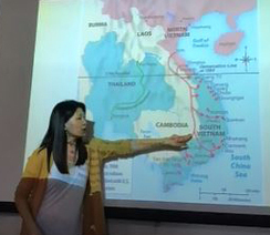 teacher pointing at image of world map projected onto a screen