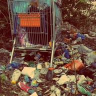 Pile of litter and debris in and around an abandoned shopping cart