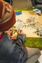 Child looking at a game card while leaning over a Bozeman Trail board game