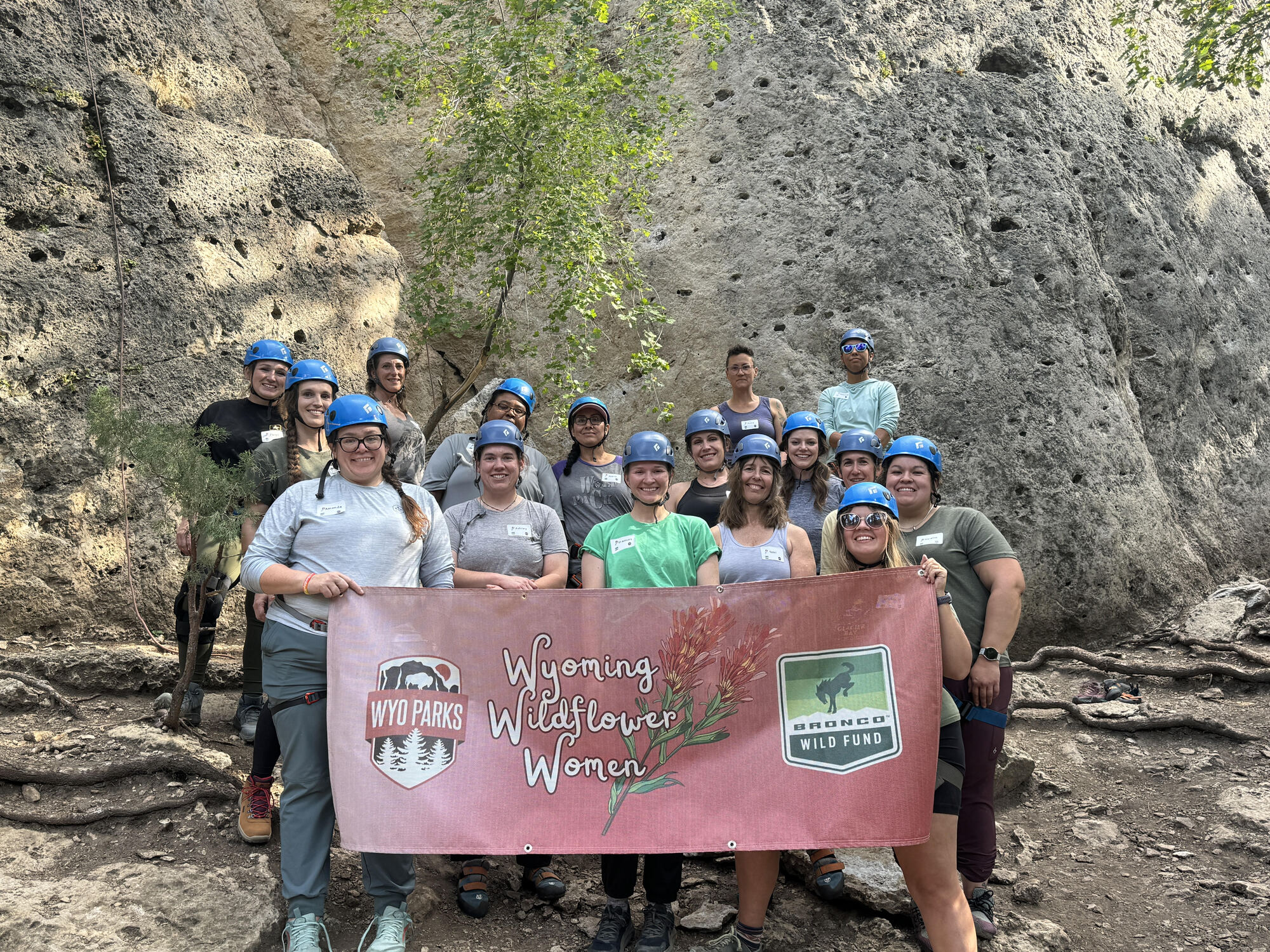 17 women in helmets holding Wyoming Wildflower Women sign