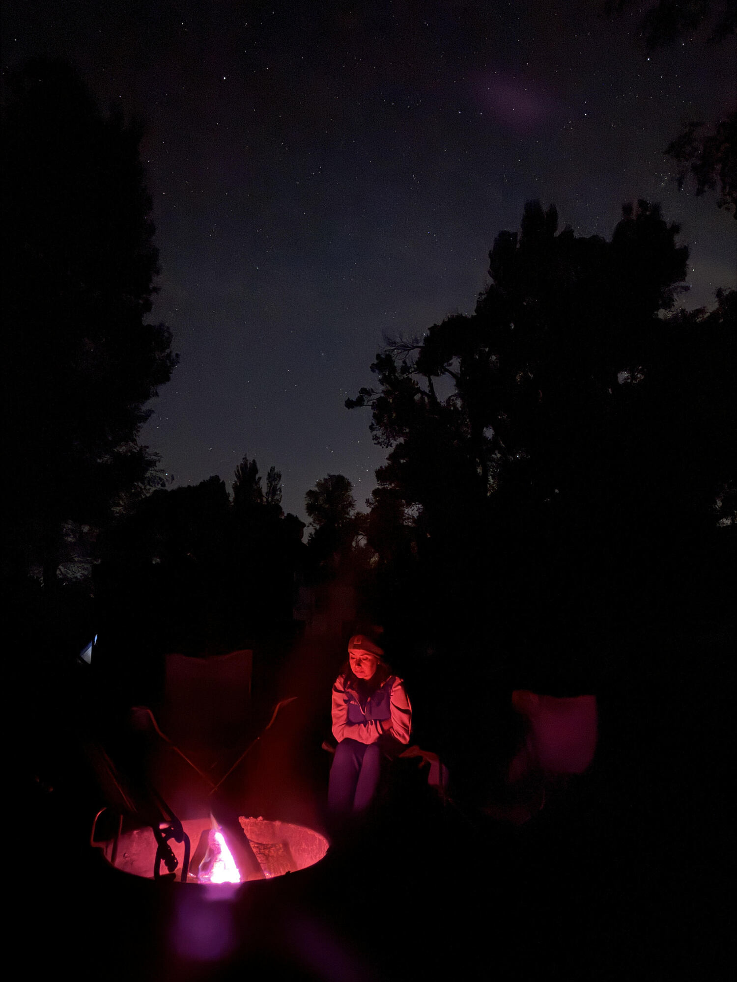 woman sitting in campfire glow with night sky