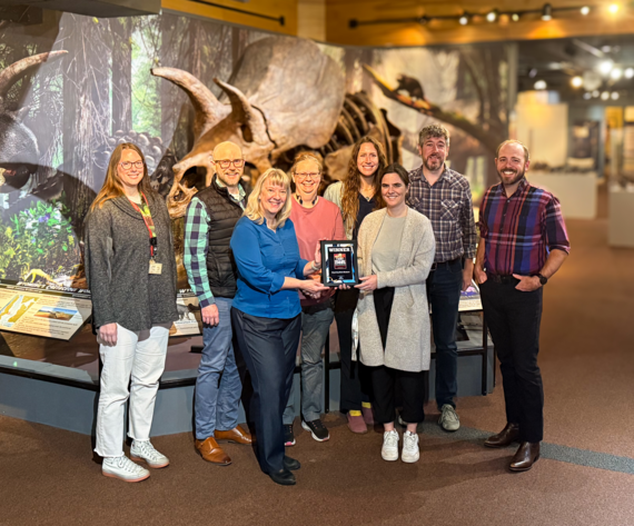 8 museum staff holding best of the best plaque