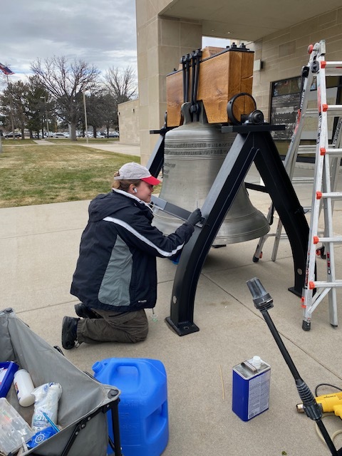 person conserving liberty bell outside of barrett building