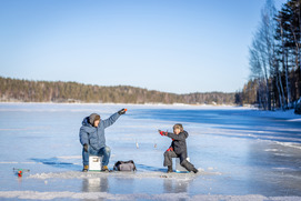 Adult and child fishing on frozen lake