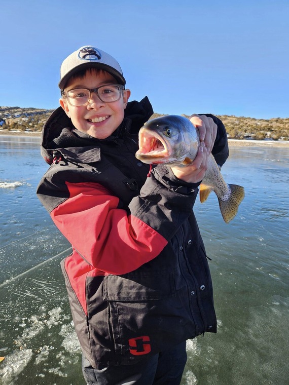 Young boy shows off his caught fish on frozen lake