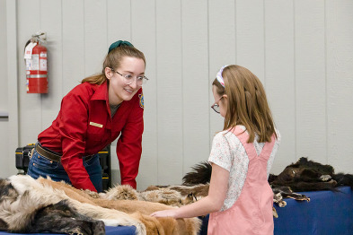 A Game and Fish employee speaks to a child at Mule Deer Days table