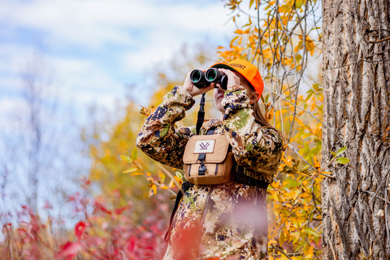 Female hunter looks for animals using binoculars