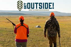 Two hunters walk through a field toward their harvested antelope