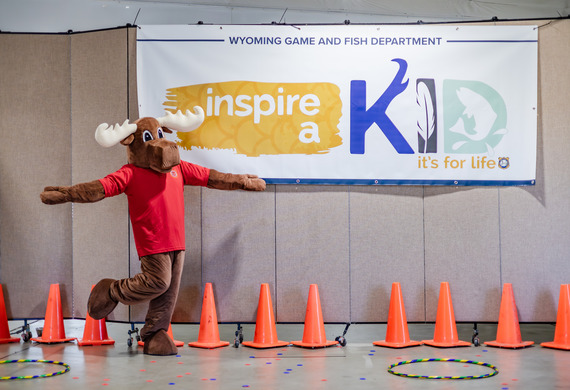 Mardy the Moose in front of the Inspire a Kid logo at Mule Deer Days