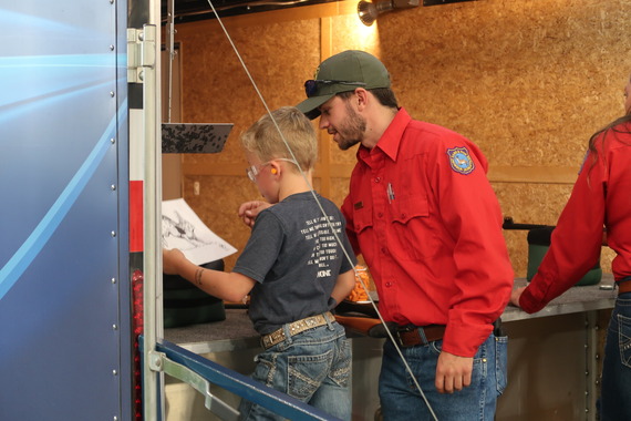 Keaton Weber helping a kid at the WGFD shooting trailer