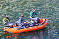 A raft of fly anglers in waders fishing in a river